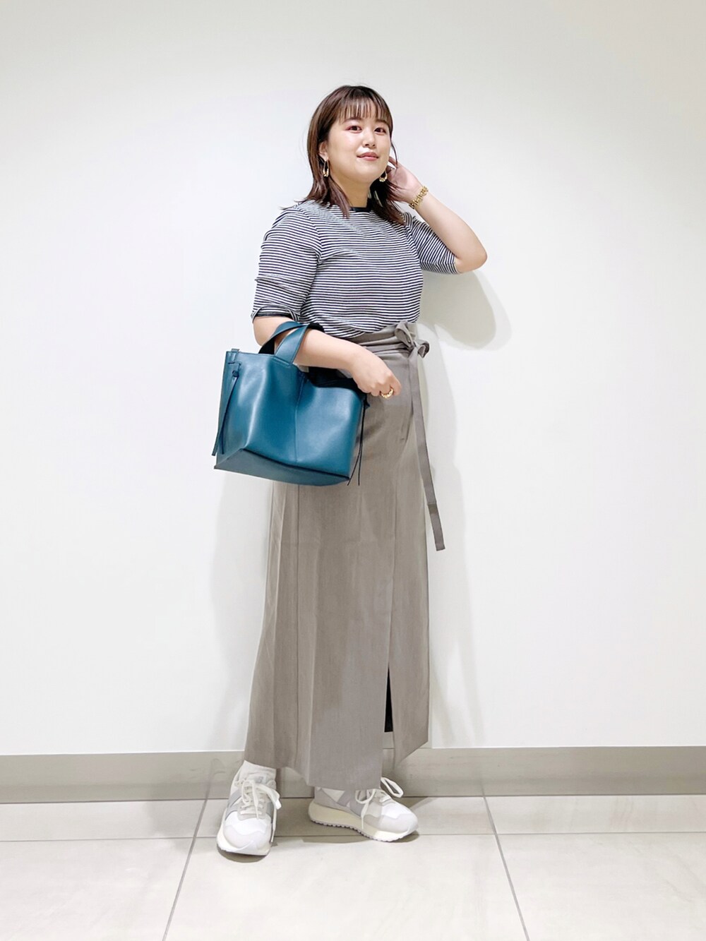 ブラウン系のスカート、ブルー系のトートバッグ、ホワイト系のスニーカーを着用したレディースの夏コーディネートの5枚目の写真