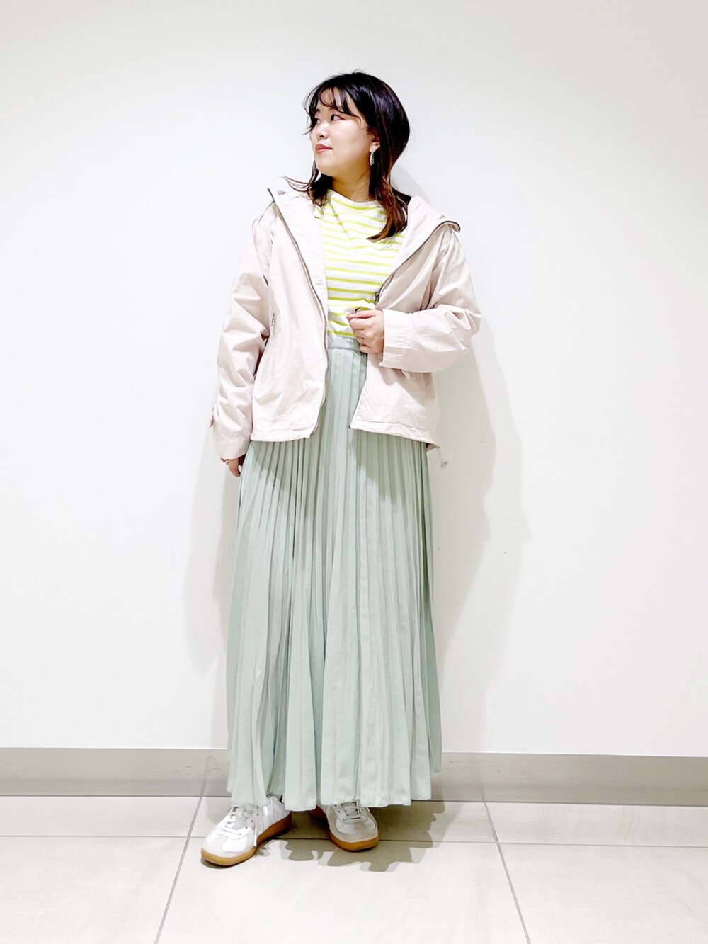 ベージュ系のブルゾン、イエロー系のTシャツ/カットソー、グリーン系のスカートを着用したレディースの春コーディネートの2枚目の写真