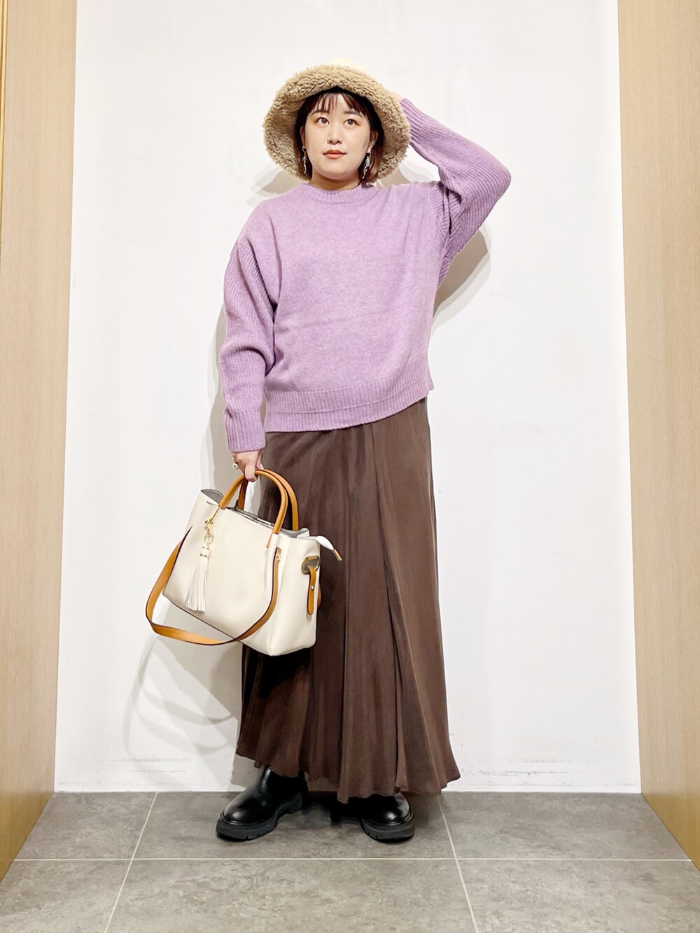 パープル系のニット/セーター、ブラウン系のスカート、ホワイト系のトートバッグを着用したレディースの冬コーディネートの2枚目の写真