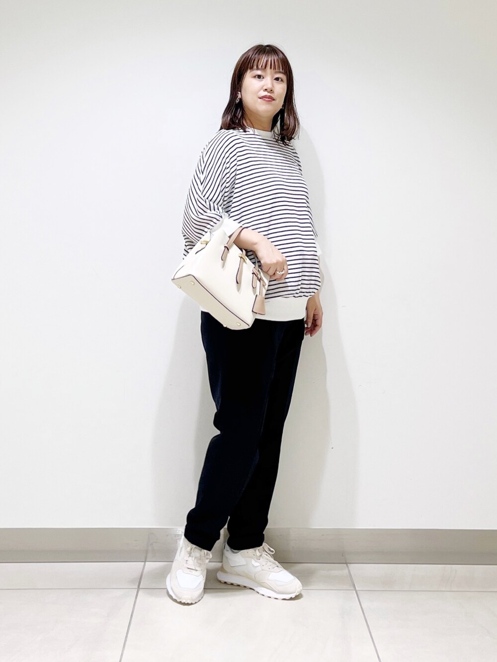 ホワイト系のTシャツ/カットソー、ブルー系のパンツ、ホワイト系のハンドバッグを着用したレディースの秋コーディネートの9枚目の写真