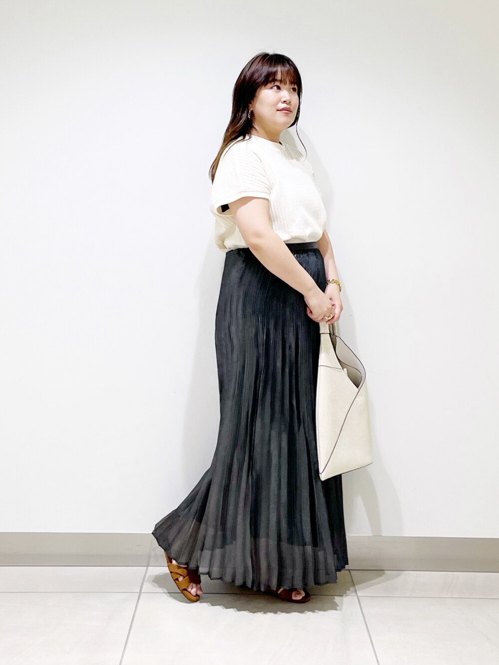 ブラック系のスカート、ホワイト系のニット/セーター、ホワイト系のトートバッグを着用したレディースの夏コーディネートの7枚目の写真