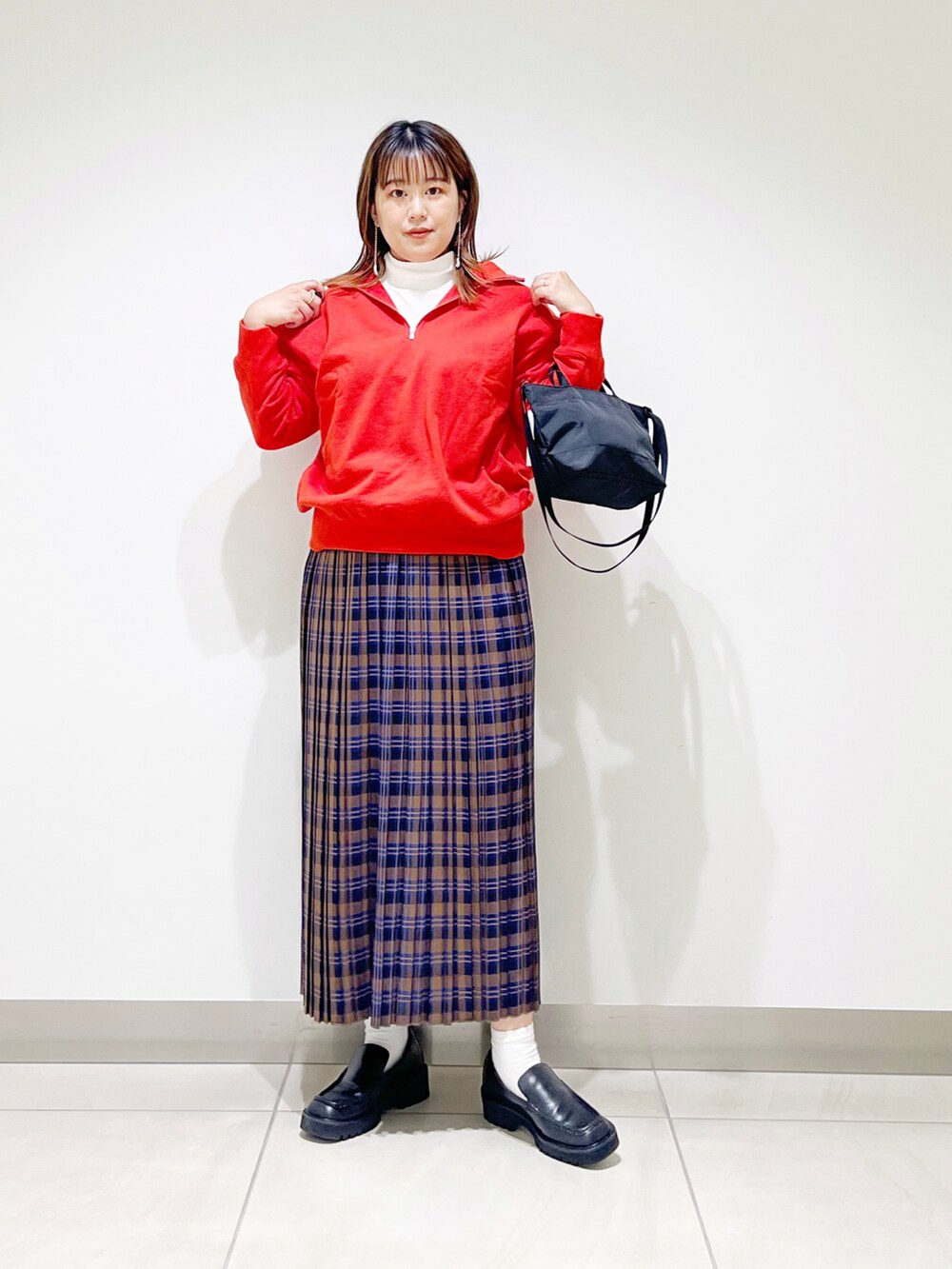 オレンジ系のスウェット、ブルー系のスカート、ブラック系のショルダーバッグを着用したレディースの秋コーディネートの4枚目の写真