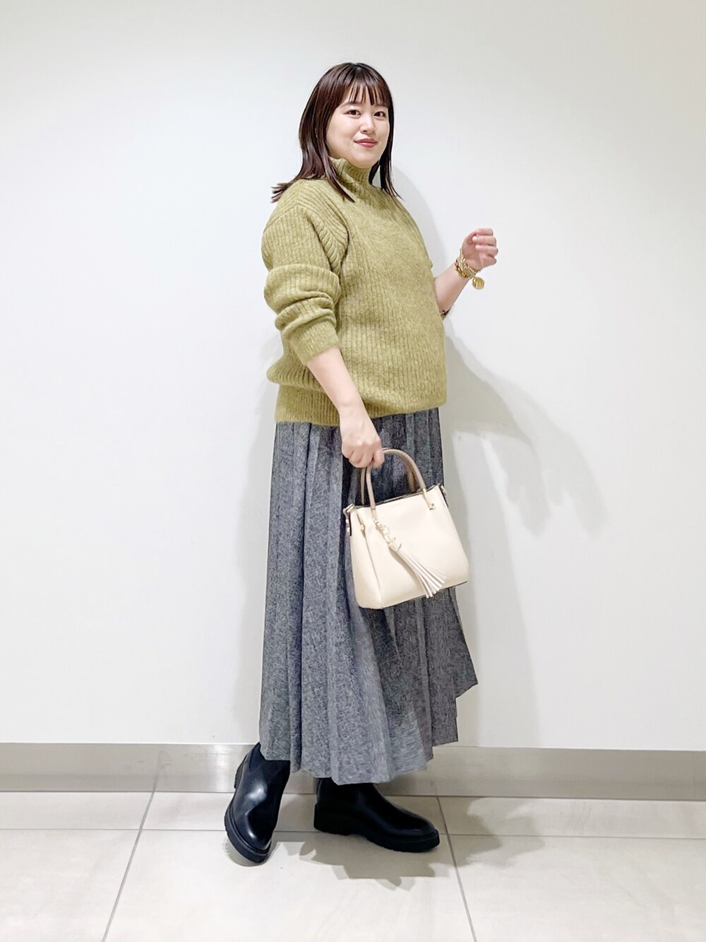 グリーン系のニット/セーター、ブルー系のスカート、ホワイト系のトートバッグを着用したレディースの冬コーディネートの9枚目の写真