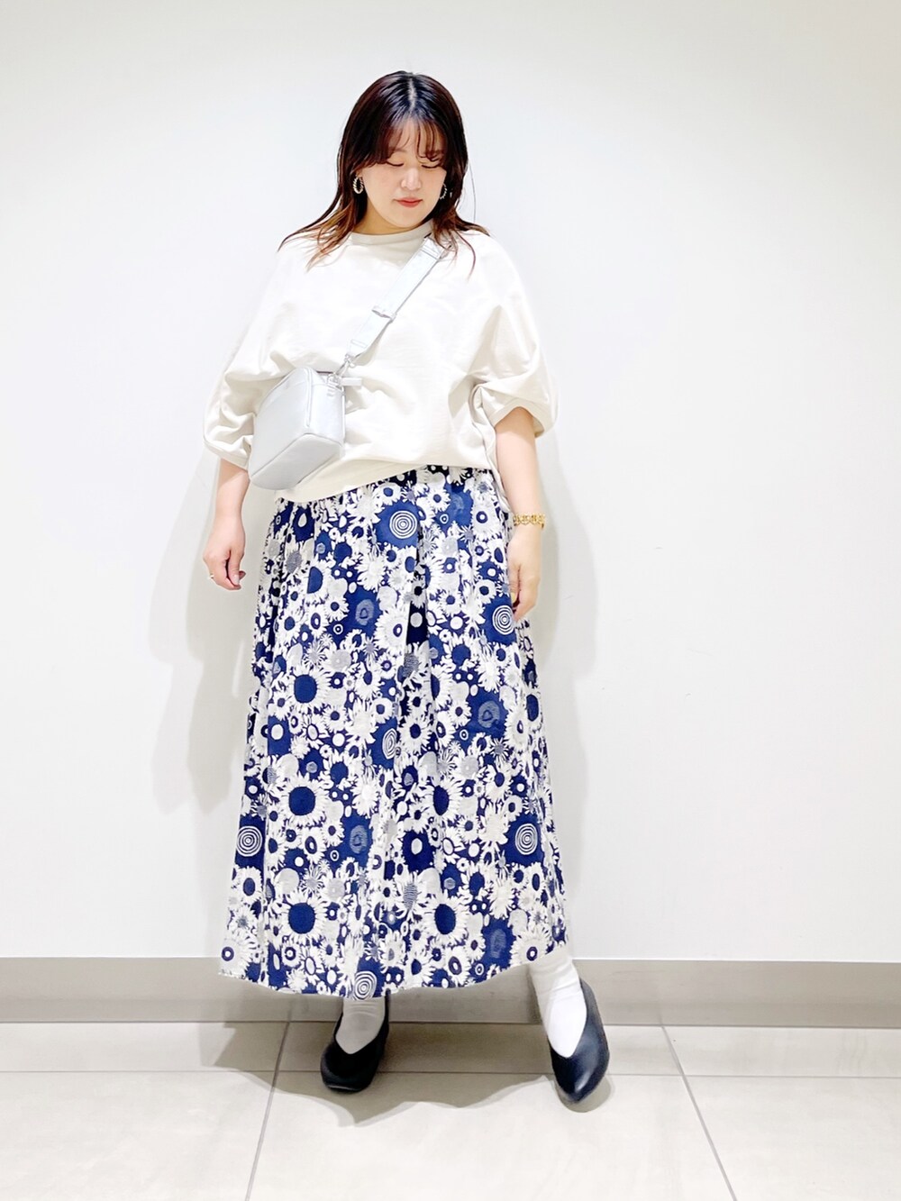 ベージュ系のTシャツ/カットソー、ブルー系のスカート、ブラック系のパンプスを着用したレディースの春コーディネートの3枚目の写真