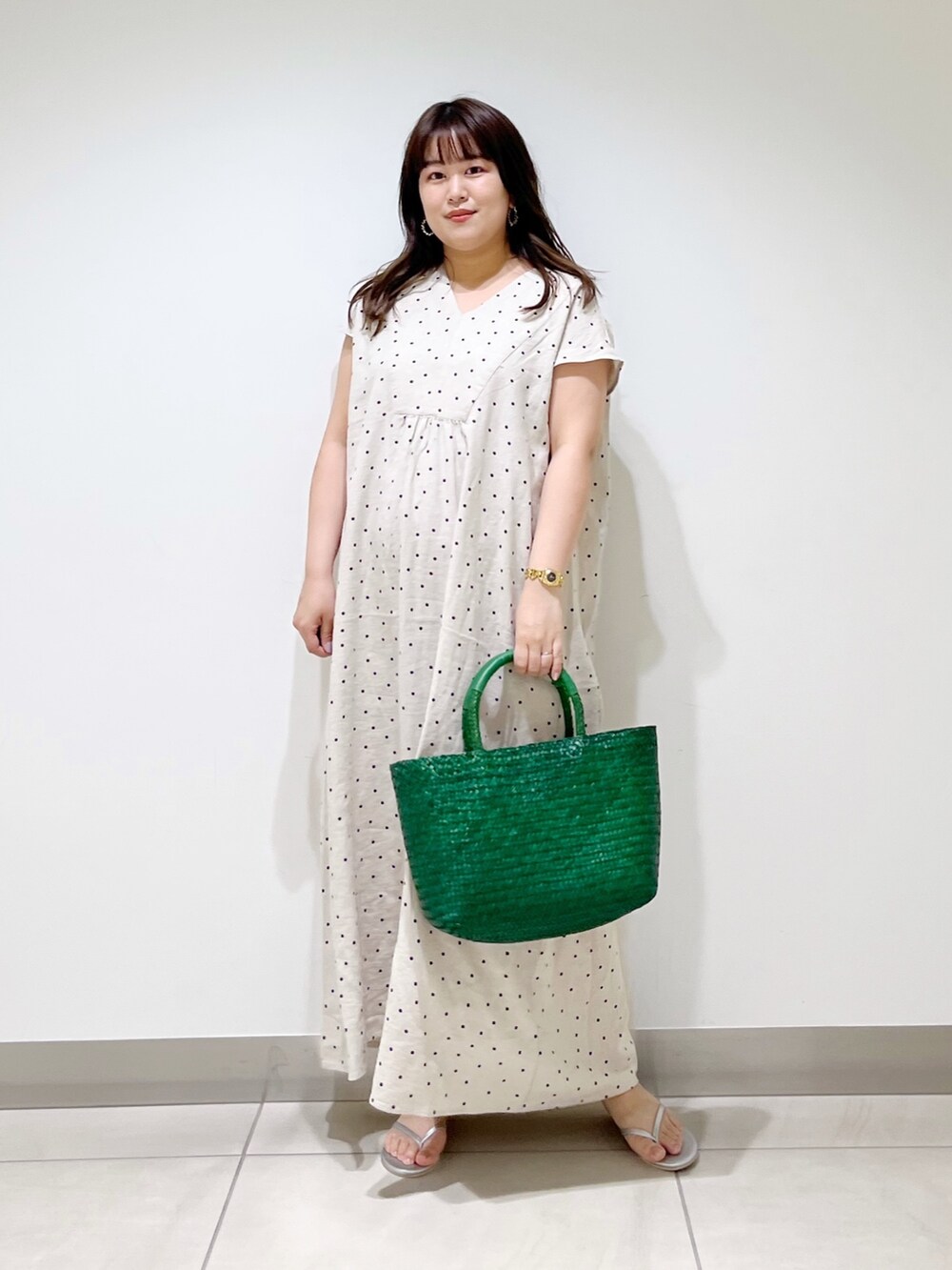 ベージュ系のワンピース、グリーン系のハンドバッグ、シルバー系のサンダルを着用したレディースの春コーディネートの3枚目の写真