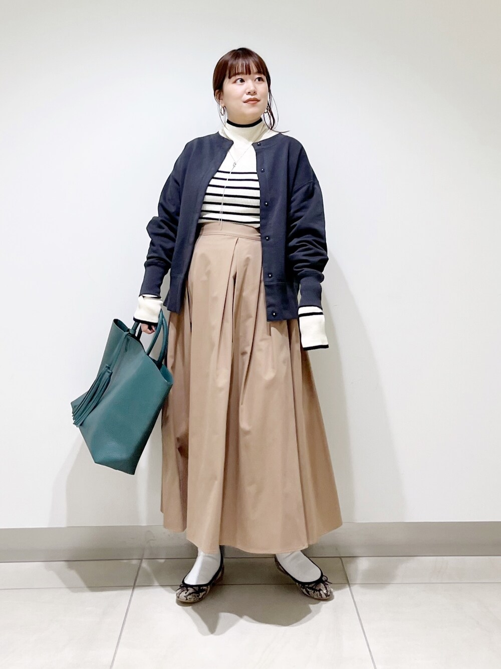 グリーン系のトートバッグ、ベージュ系のスカート、その他のバレエシューズを着用したレディースの秋コーディネートの10枚目の写真