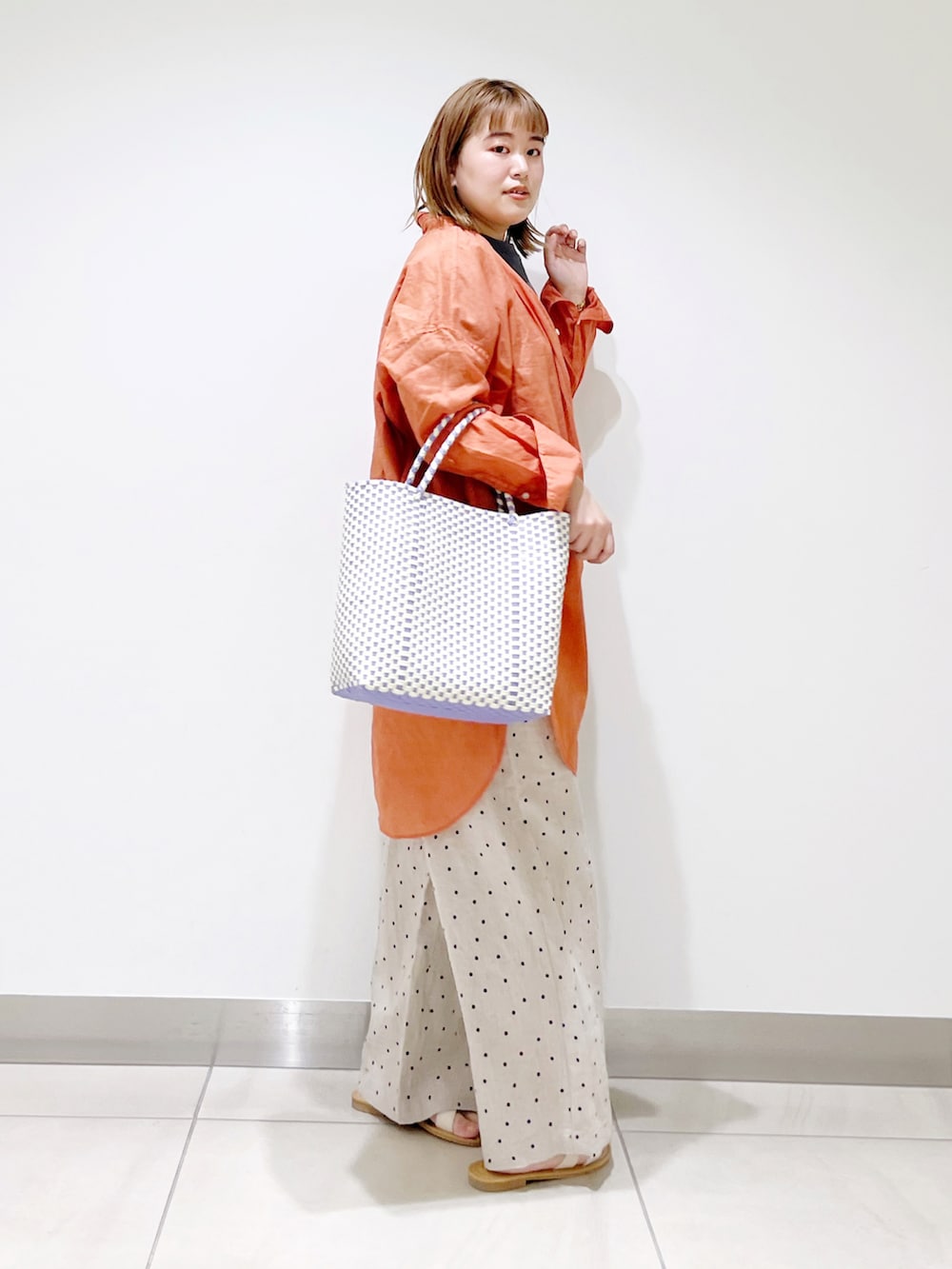 オレンジ系のシャツ/ブラウス、グリーン系のTシャツ/カットソー、パープル系のトートバッグを着用したレディースの春コーディネートの5枚目の写真