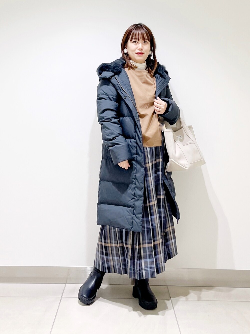 イエロー系のTシャツ/カットソー、ブラック系のダウンジャケット/コート、ブルー系のスカートを着用したレディースの秋コーディネートの2枚目の写真