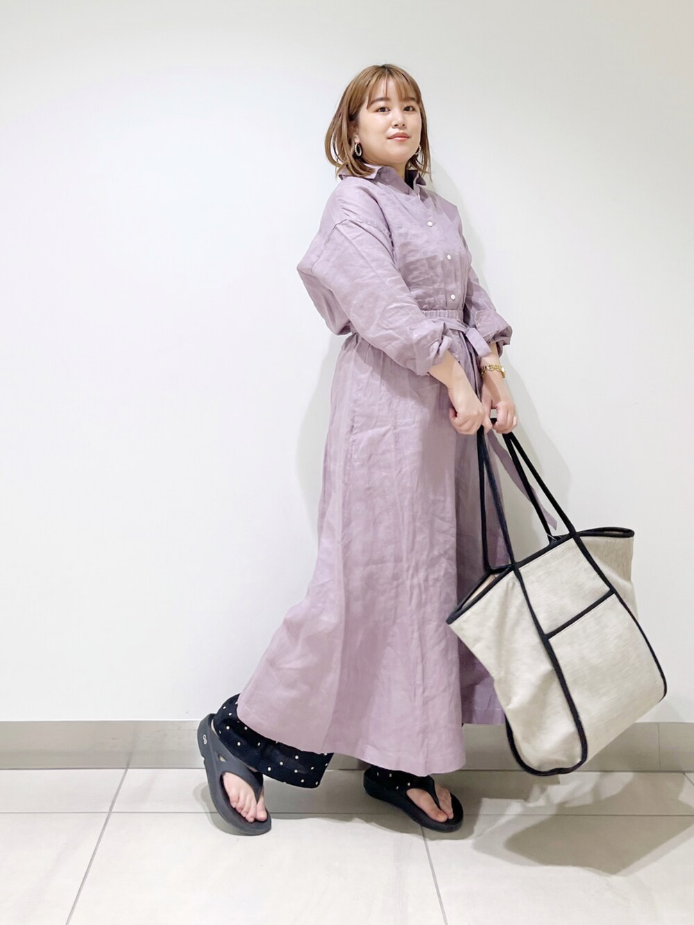 パープル系のワンピース、ブラック系のトートバッグ、ブラック系のサンダルを着用したレディースの春コーディネートの4枚目の写真