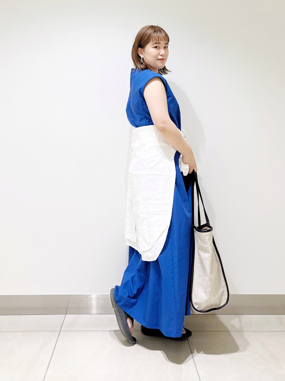 ブルー系のワンピース、ブラック系のトートバッグ、ブラック系のサンダルを着用したレディースの春コーディネートの4枚目の写真