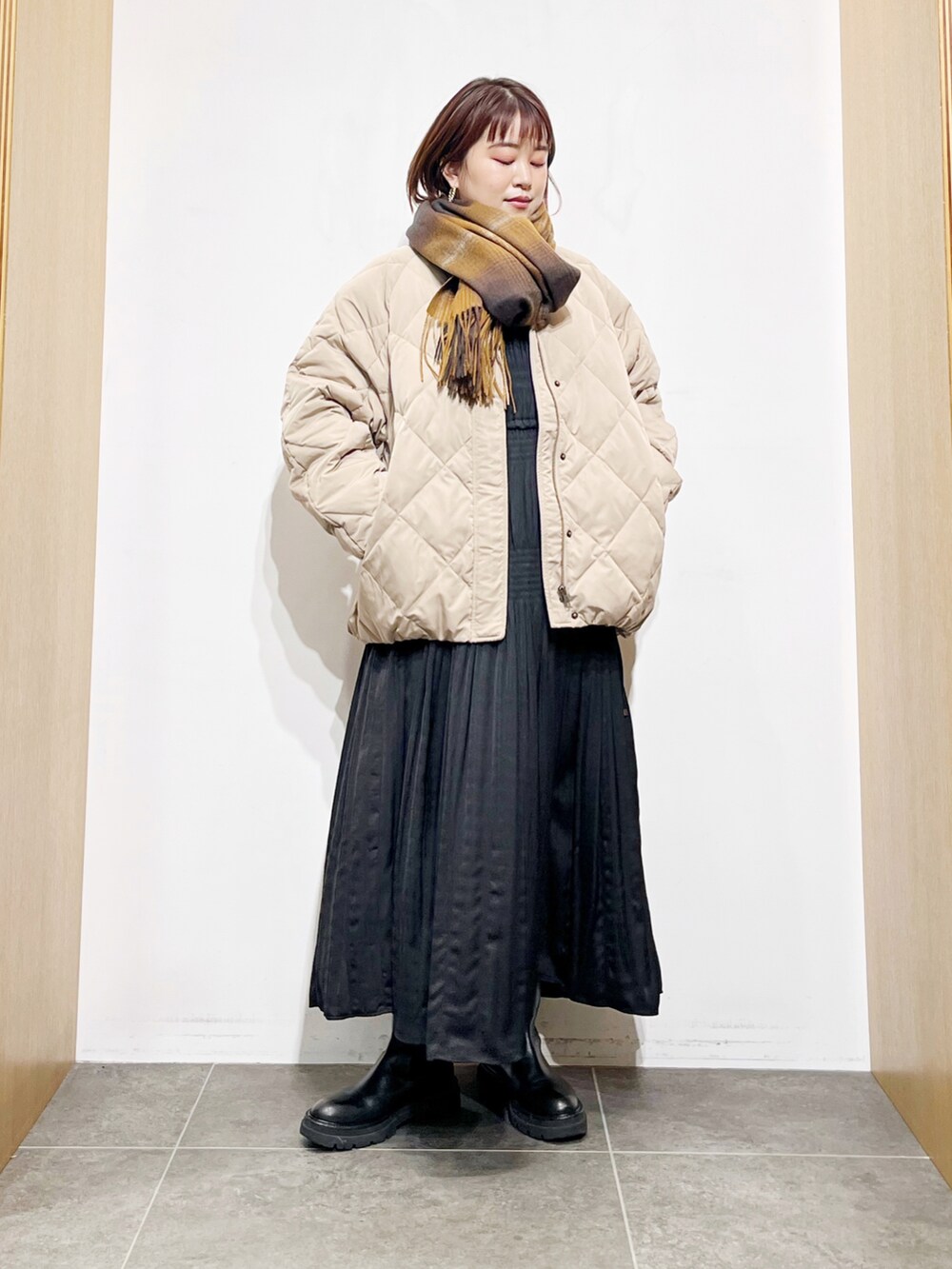 ベージュ系のダウンジャケット/コート、ブラック系のワンピース、ブラック系のブーツを着用したレディースの冬コーディネートの2枚目の写真
