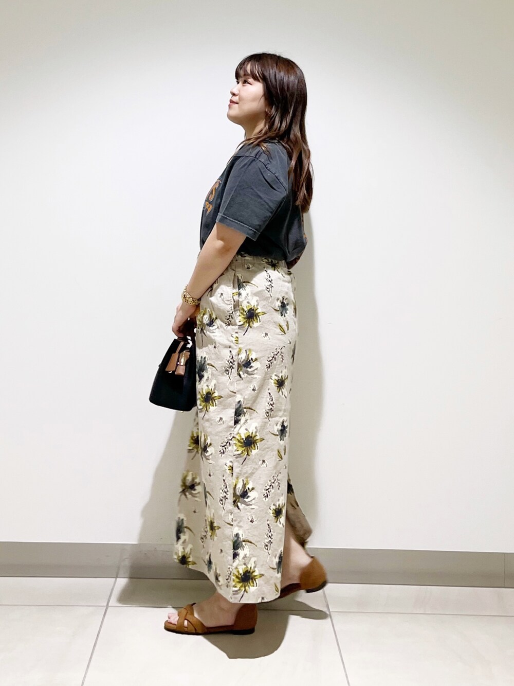 オレンジ系のTシャツ/カットソー、ブラック系のハンドバッグ、イエロー系のスカートを着用したレディースの夏コーディネートの4枚目の写真