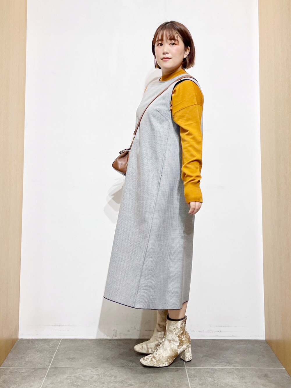 ブラック系のワンピース、ベージュ系のブーツ、ブラウン系のショルダーバッグを着用したレディースの秋コーディネートの2枚目の写真