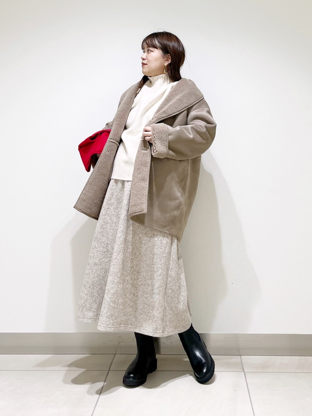 グレー系のムートンコート、ホワイト系のニット/セーター、ベージュ系のスカートを着用したレディースの冬コーディネートの9枚目の写真
