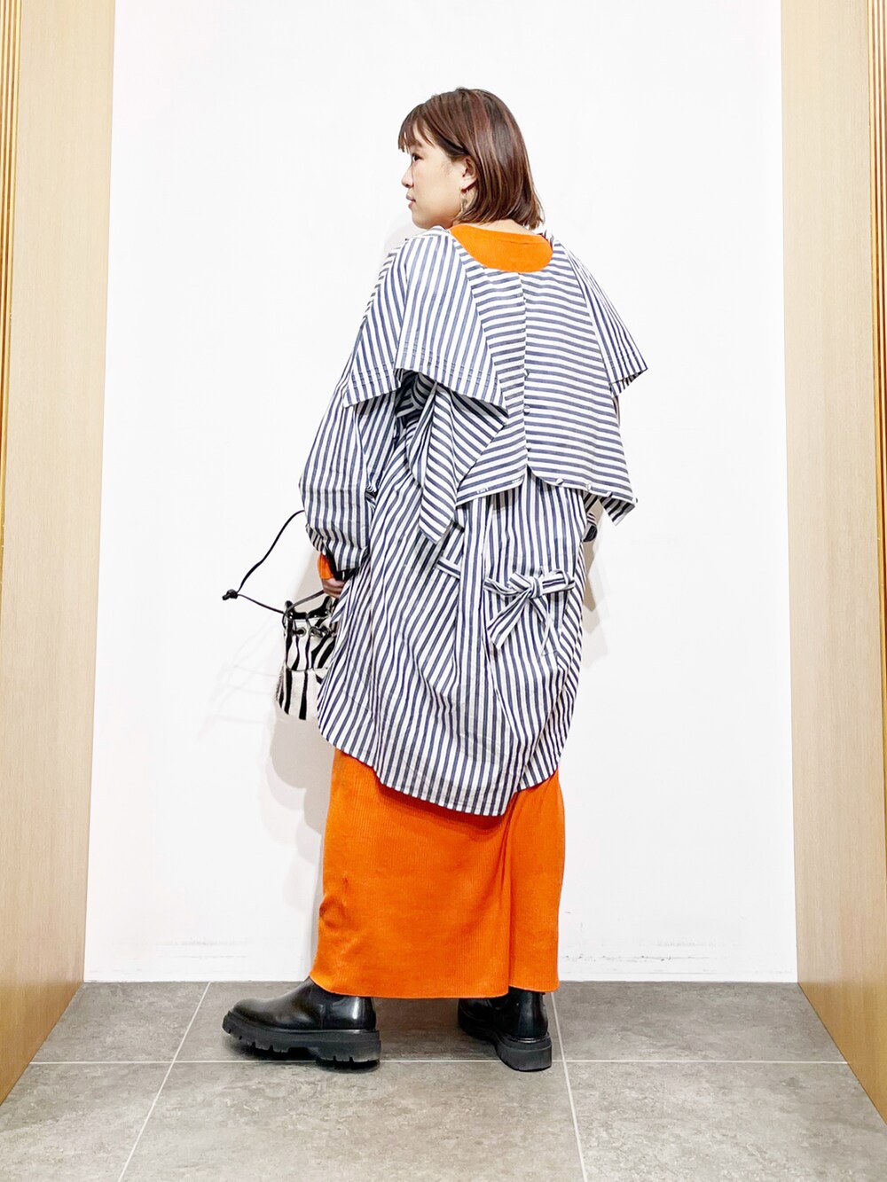 ブルー系のシャツ/ブラウス、オレンジ系のワンピース、ブラック系のブーツを着用したレディースの冬コーディネートの3枚目の写真