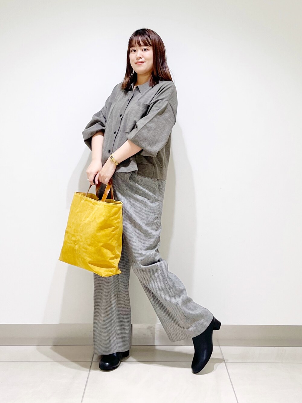 グレー系のニット/セーター、ベージュ系のパンツ、イエロー系のトートバッグを着用したレディースの秋コーディネートの4枚目の写真