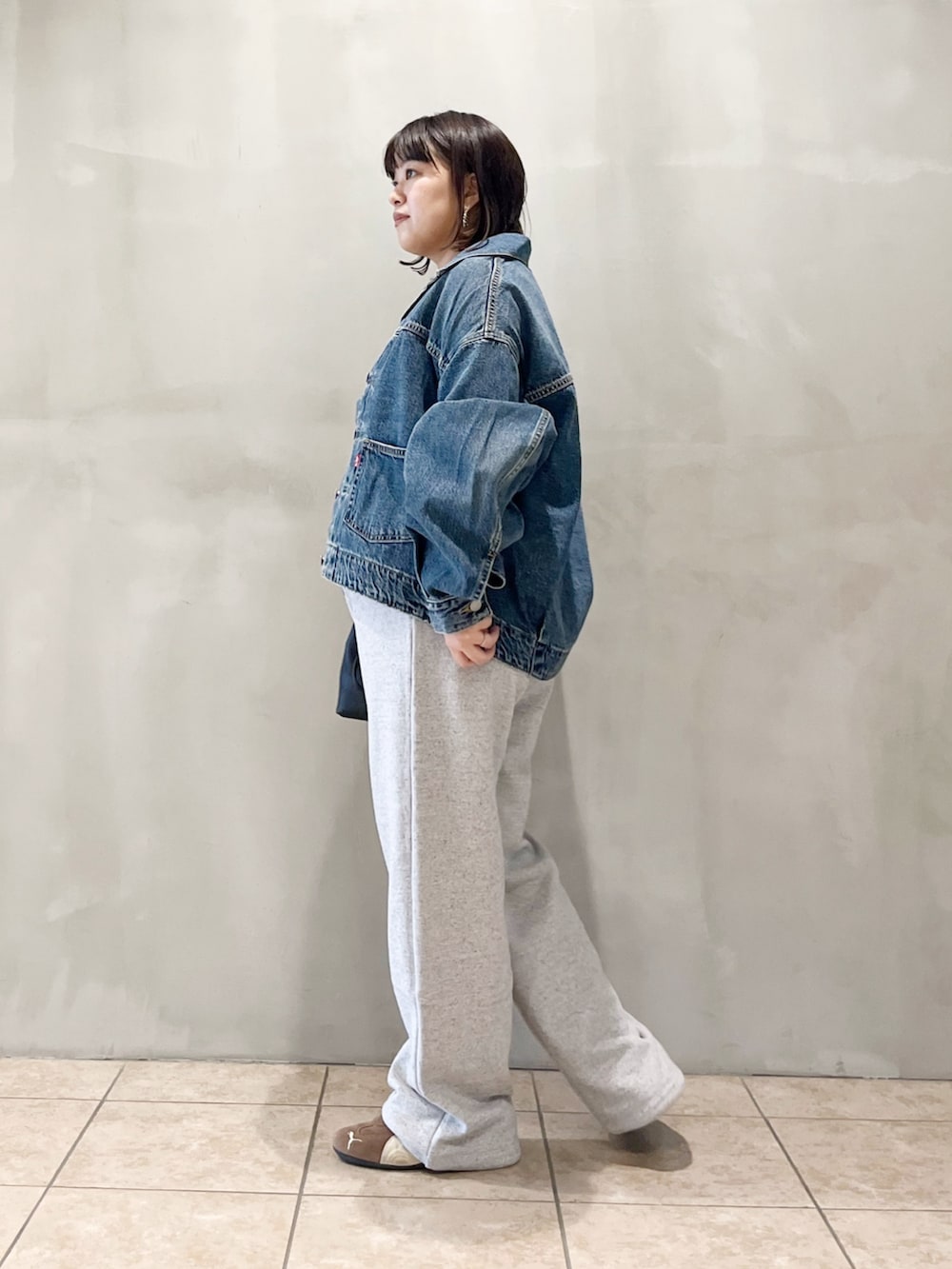 ブルー系のデニムジャケット、ブラック系のスニーカー、グレー系のその他パンツを着用したレディースの秋コーディネートの6枚目の写真