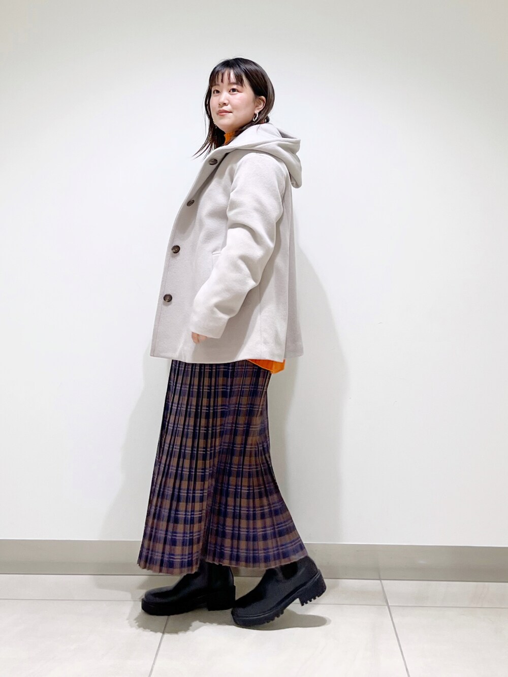 ベージュ系のその他アウター、オレンジ系のニット/セーター、ブルー系のスカートを着用したレディースの秋コーディネートの5枚目の写真