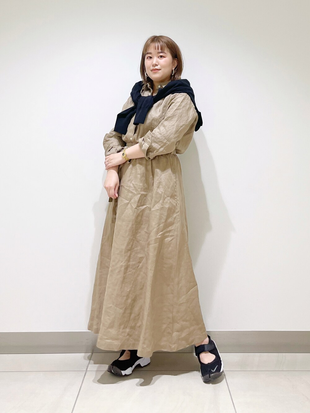 ベージュ系のワンピース、ブラック系のカーディガン/ボレロ、ブラック系のスニーカーを着用したレディースの春コーディネートの2枚目の写真