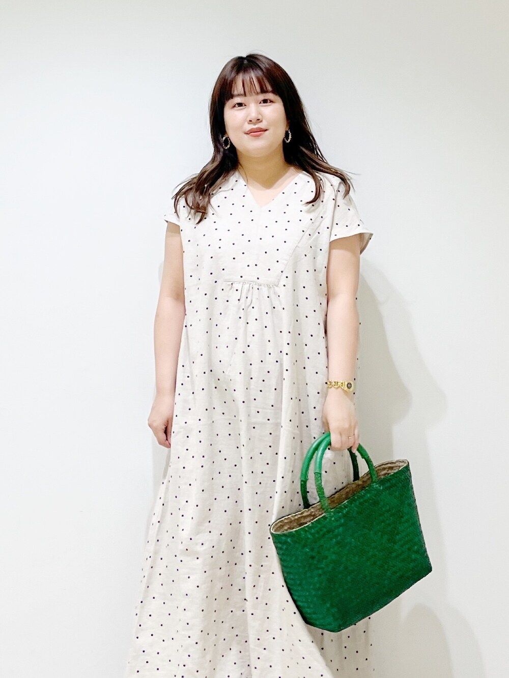 ベージュ系のワンピース、グリーン系のハンドバッグ、シルバー系のサンダルを着用したレディースの春コーディネートの5枚目の写真
