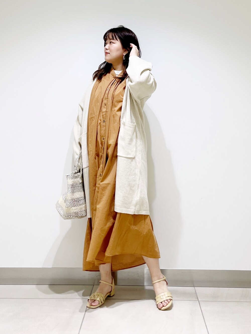 ブラウン系のワンピース、ホワイト系のカーディガン/ボレロ、ホワイト系のハンドバッグを着用したレディースの春コーディネートの2枚目の写真