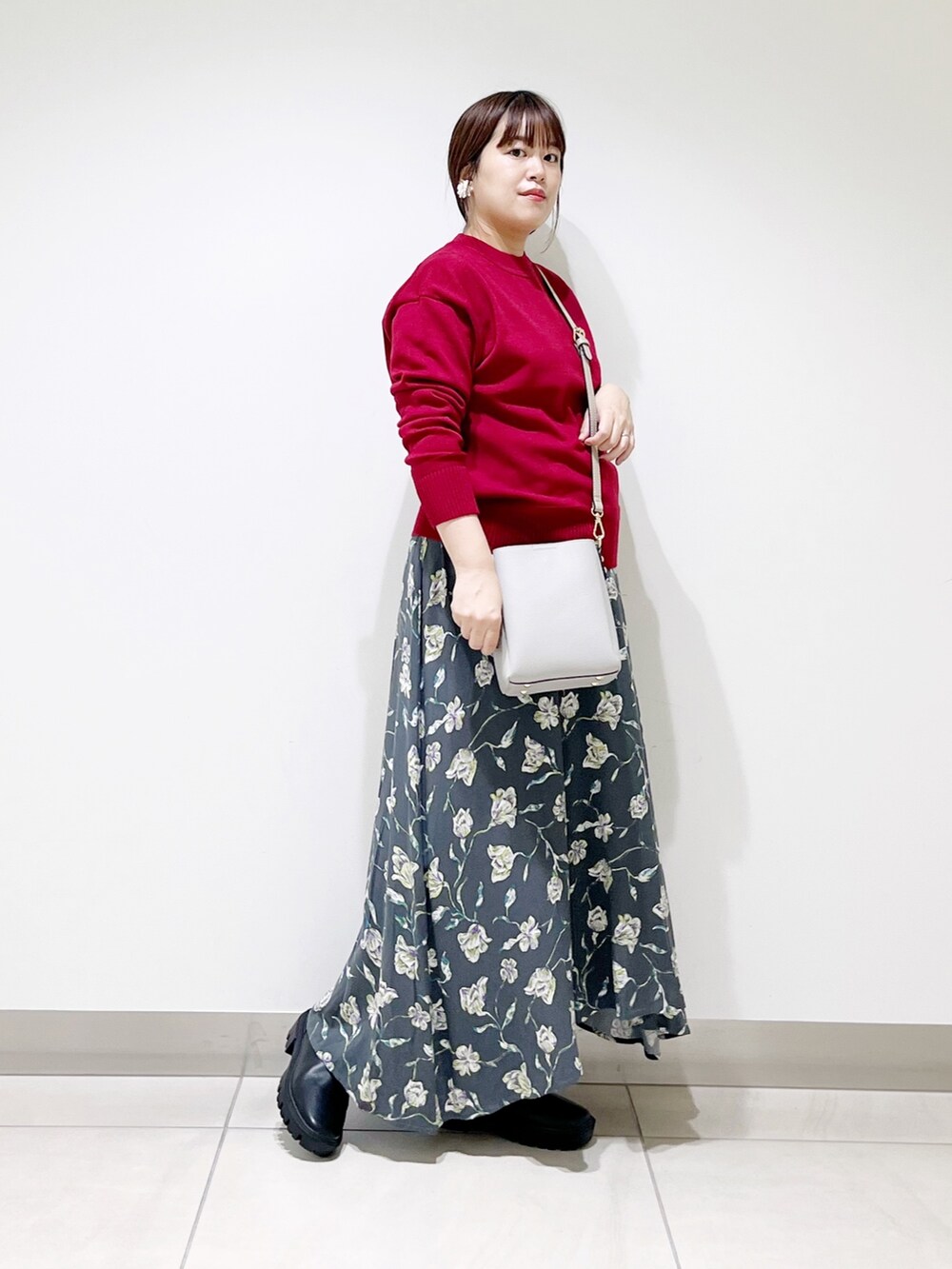 レッド系のトップス、グレー系のスカート、グレー系のショルダーバッグを着用したレディースの秋コーディネートの8枚目の写真