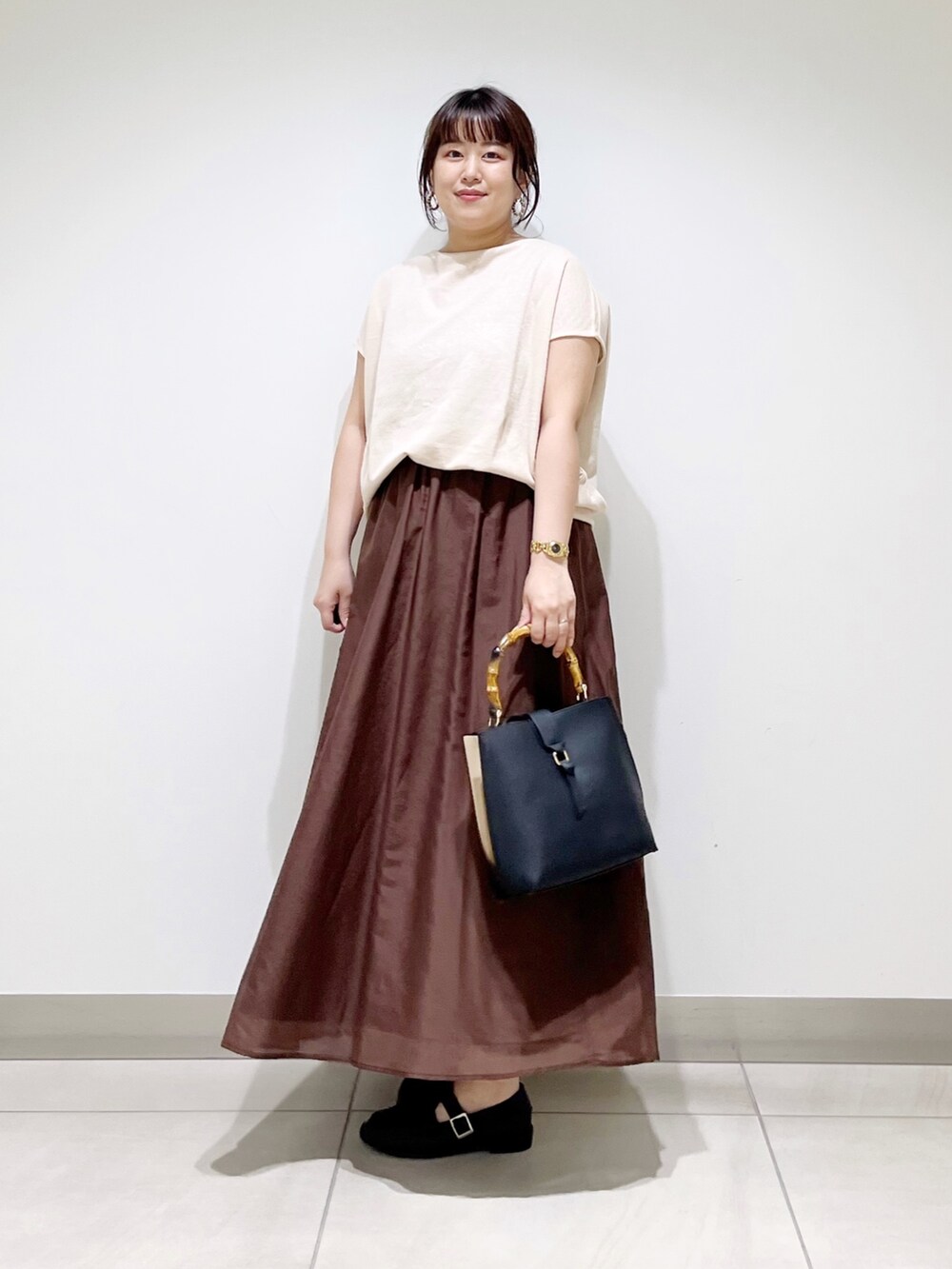 ベージュ系のTシャツ/カットソー、ブラウン系のスカート、ブラック系のハンドバッグを着用したレディースの夏コーディネートの2枚目の写真