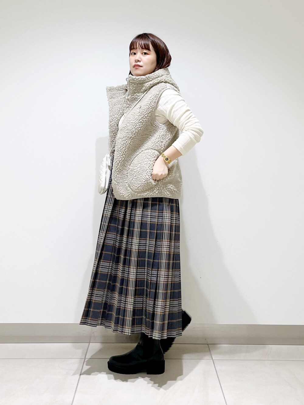 ホワイト系のトップス、グレー系のスカート、ブラック系のブーツを着用したレディースの秋コーディネートの6枚目の写真