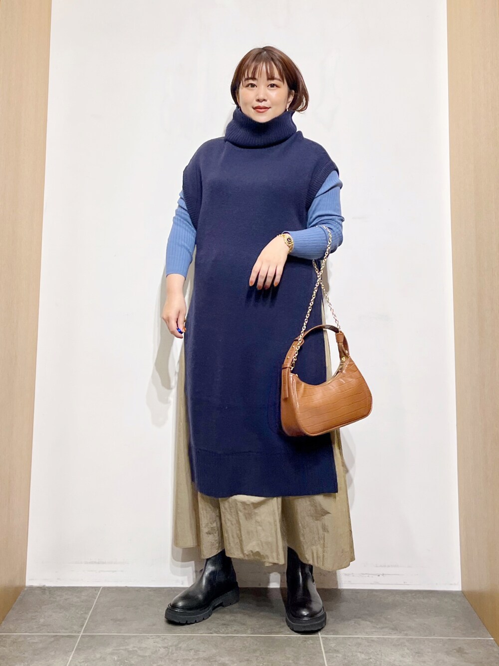 ブルー系のワンピース、ブラック系のブーツ、ベージュ系のスカートを着用したレディースの秋コーディネートの5枚目の写真