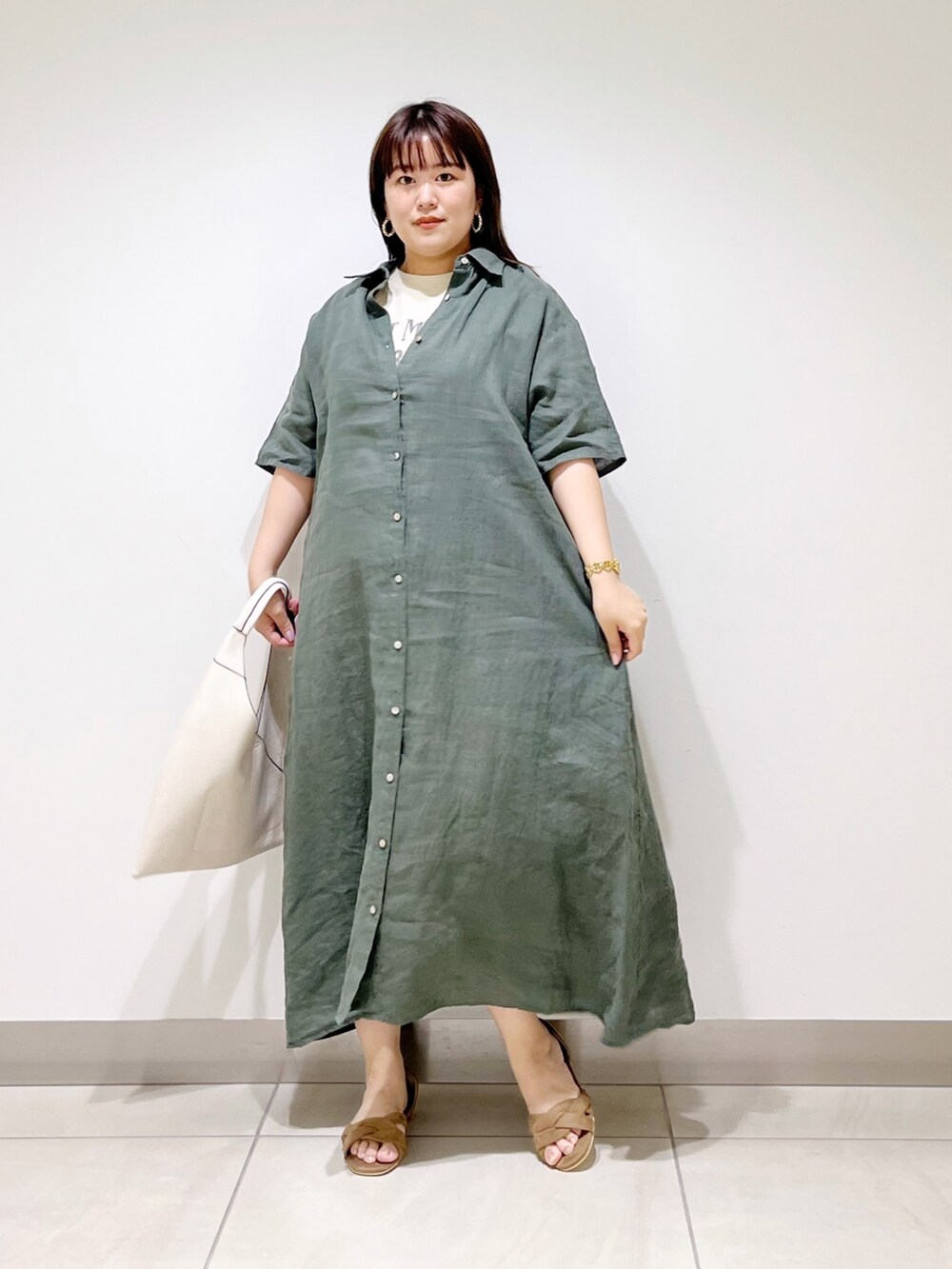 グリーン系のワンピース、ホワイト系のトートバッグ、ベージュ系のサンダルを着用したレディースの春コーディネートの3枚目の写真