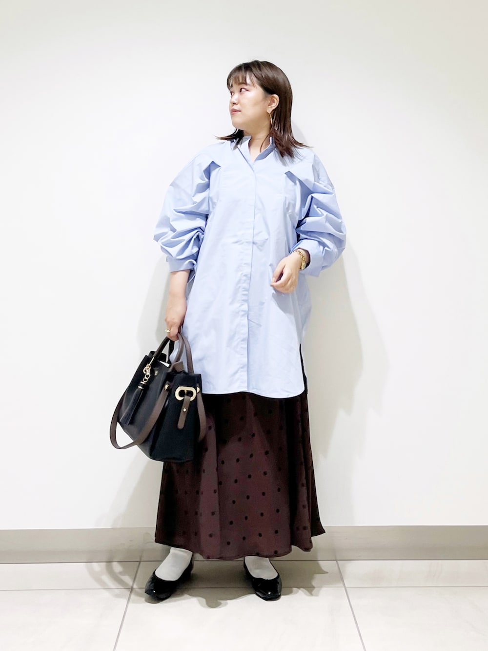 パープル系のワンピース、ブラック系のトートバッグ、ブラウン系のスカートを着用したレディースの秋コーディネートの3枚目の写真