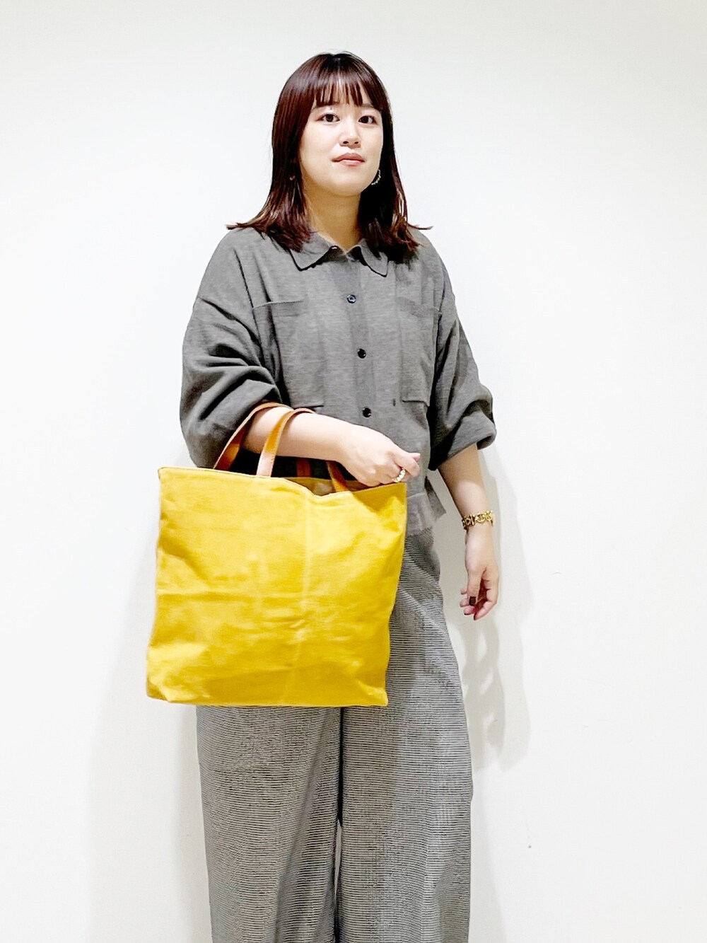 グレー系のニット/セーター、ベージュ系のパンツ、イエロー系のトートバッグを着用したレディースの秋コーディネートの5枚目の写真