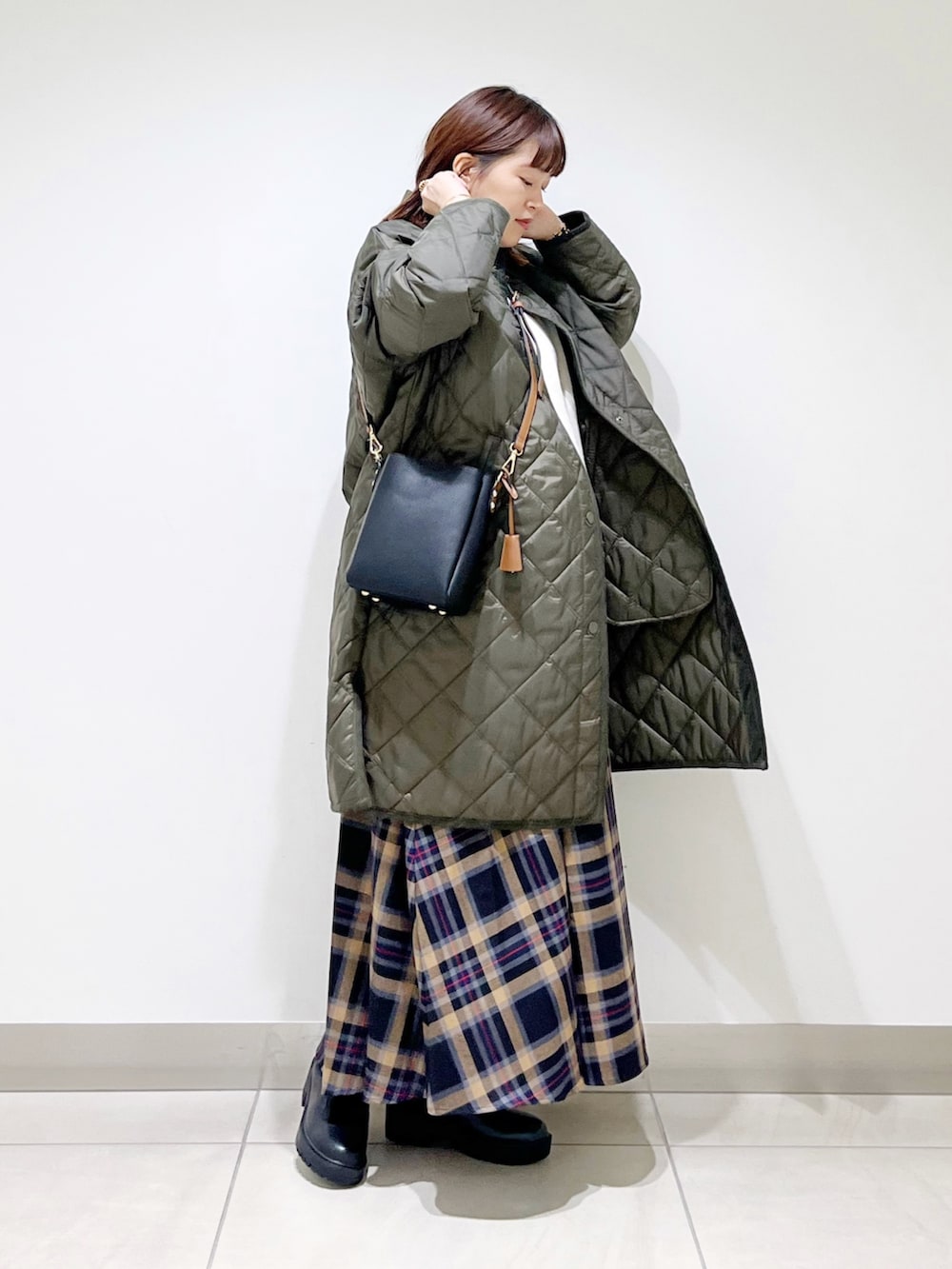 グリーン系のダウンジャケット/コート、ホワイト系のトップス、ブラウン系のスカートを着用したレディースの秋コーディネートの4枚目の写真