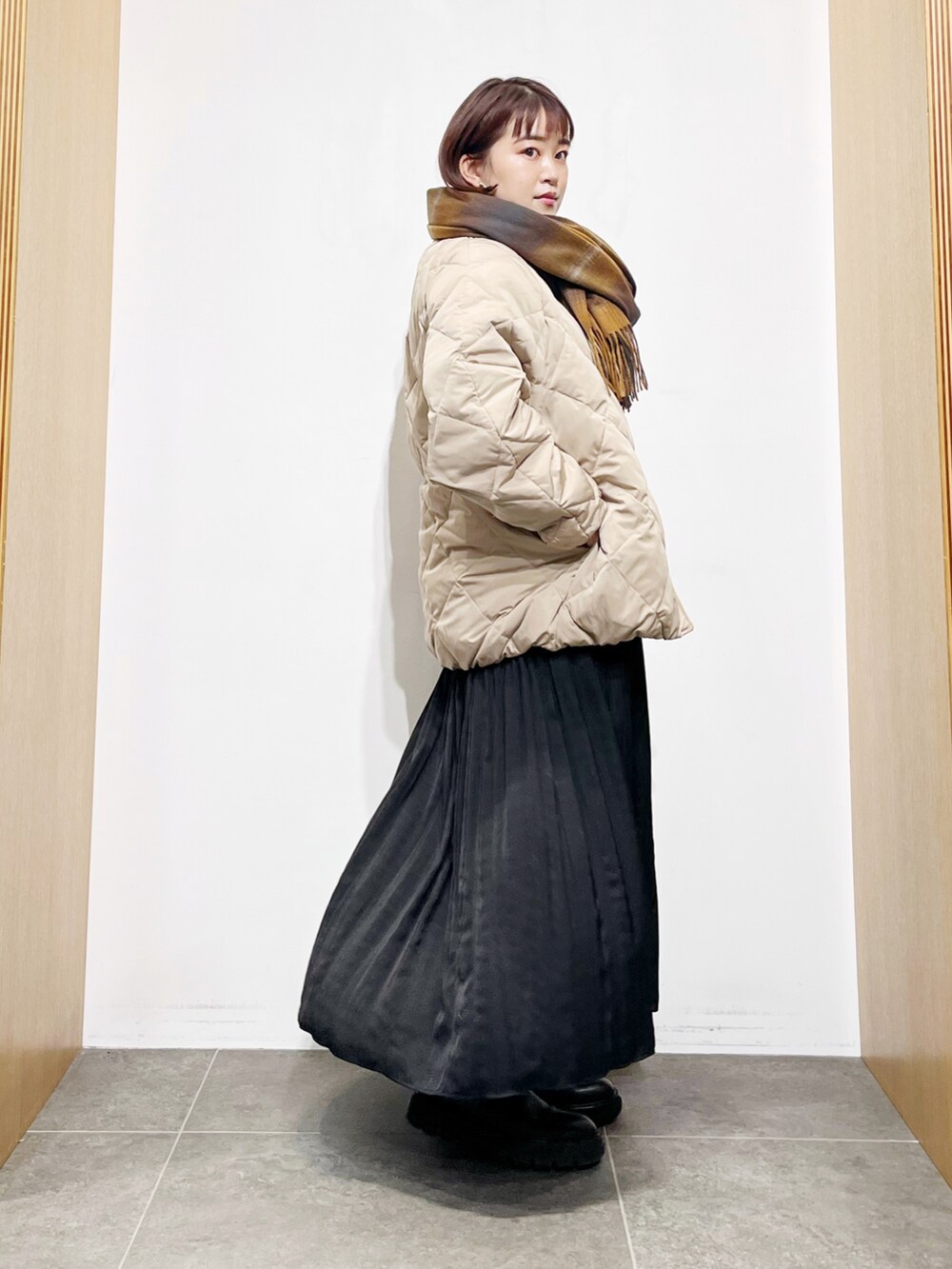 ベージュ系のダウンジャケット/コート、ブラック系のワンピース、ブラック系のブーツを着用したレディースの冬コーディネートの5枚目の写真