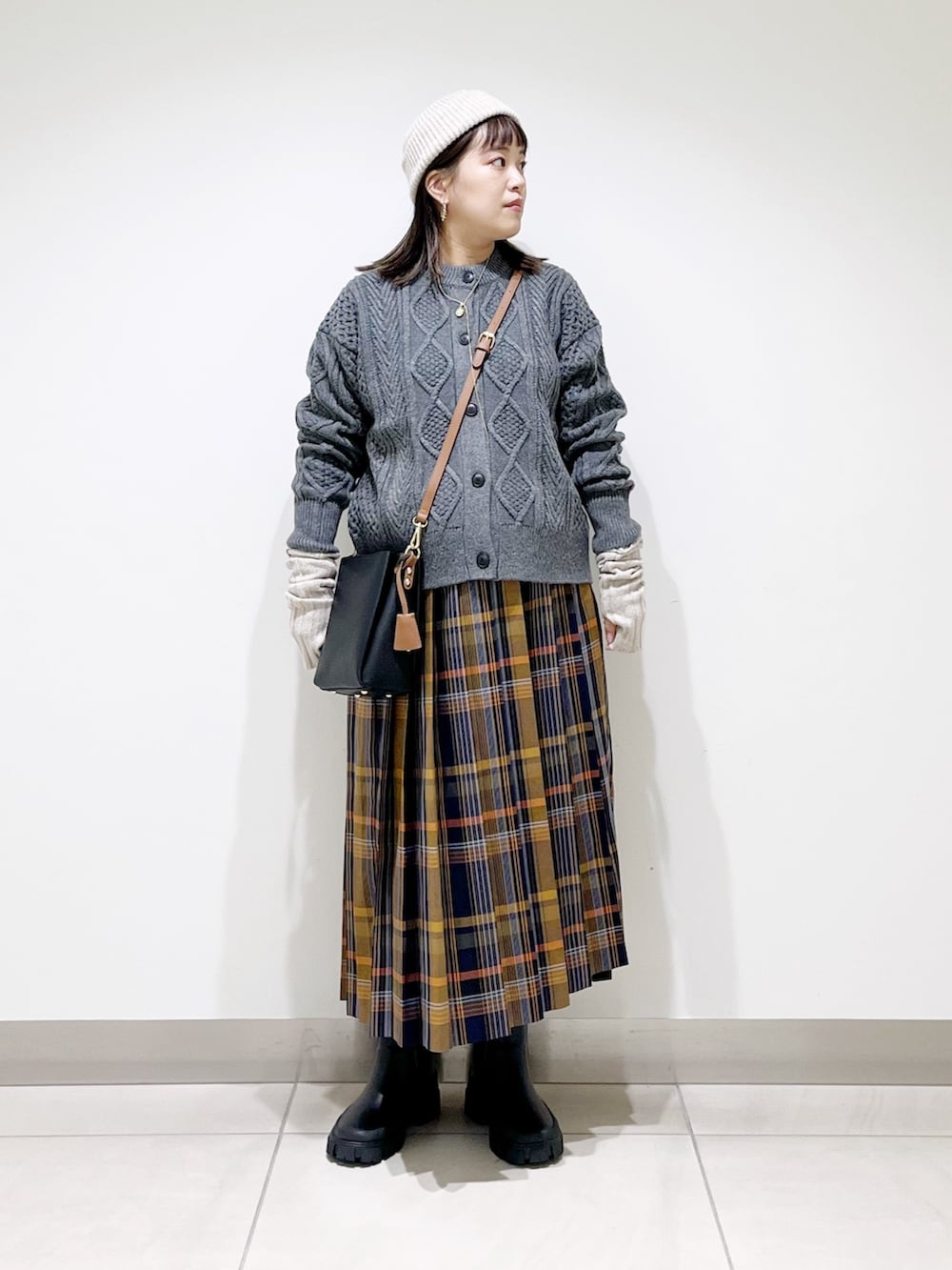 グレー系のカーディガン/ボレロ、ブルー系のスカート、ブラック系のショルダーバッグを着用したレディースの冬コーディネートの3枚目の写真