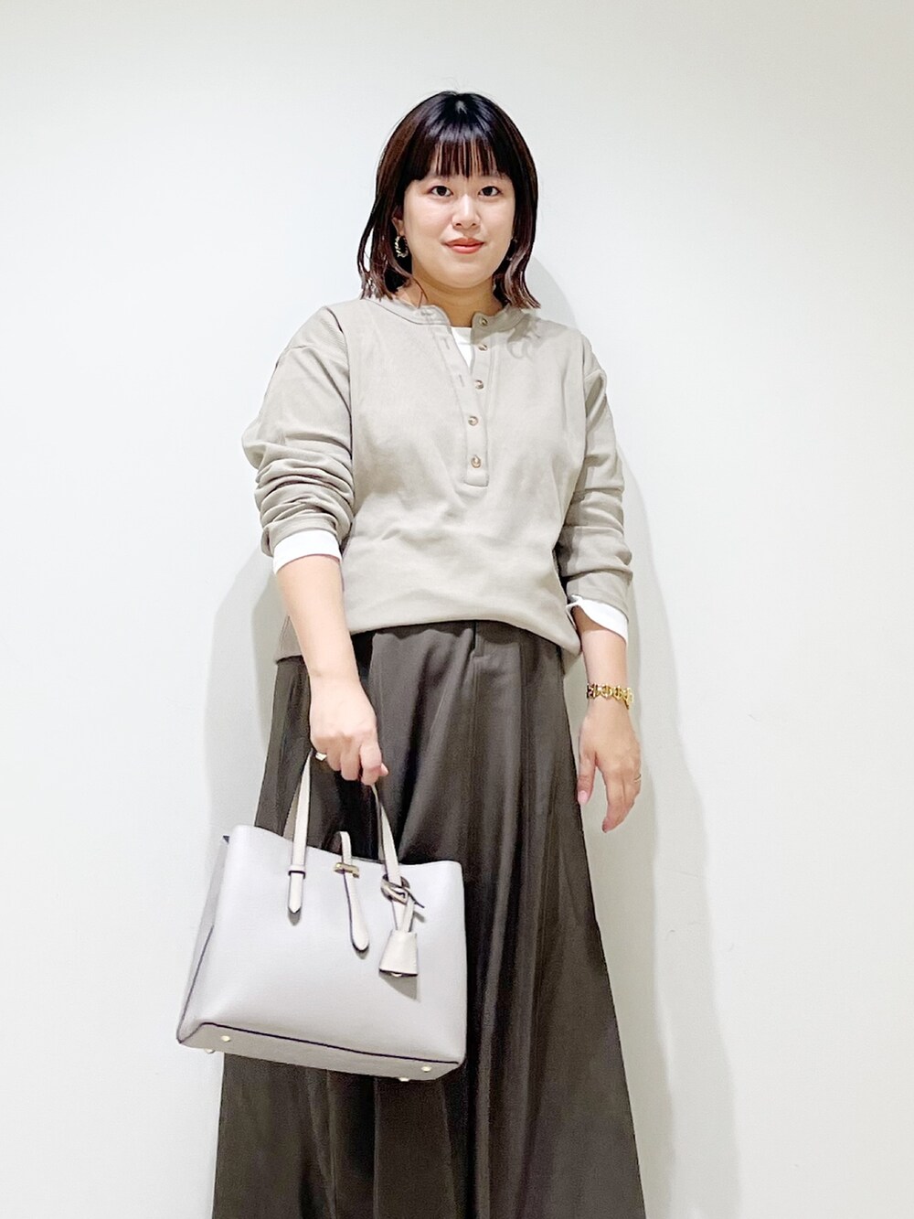 ベージュ系のTシャツ/カットソー、ブラウン系のスカート、グレー系のトートバッグを着用したレディースの秋コーディネートの4枚目の写真