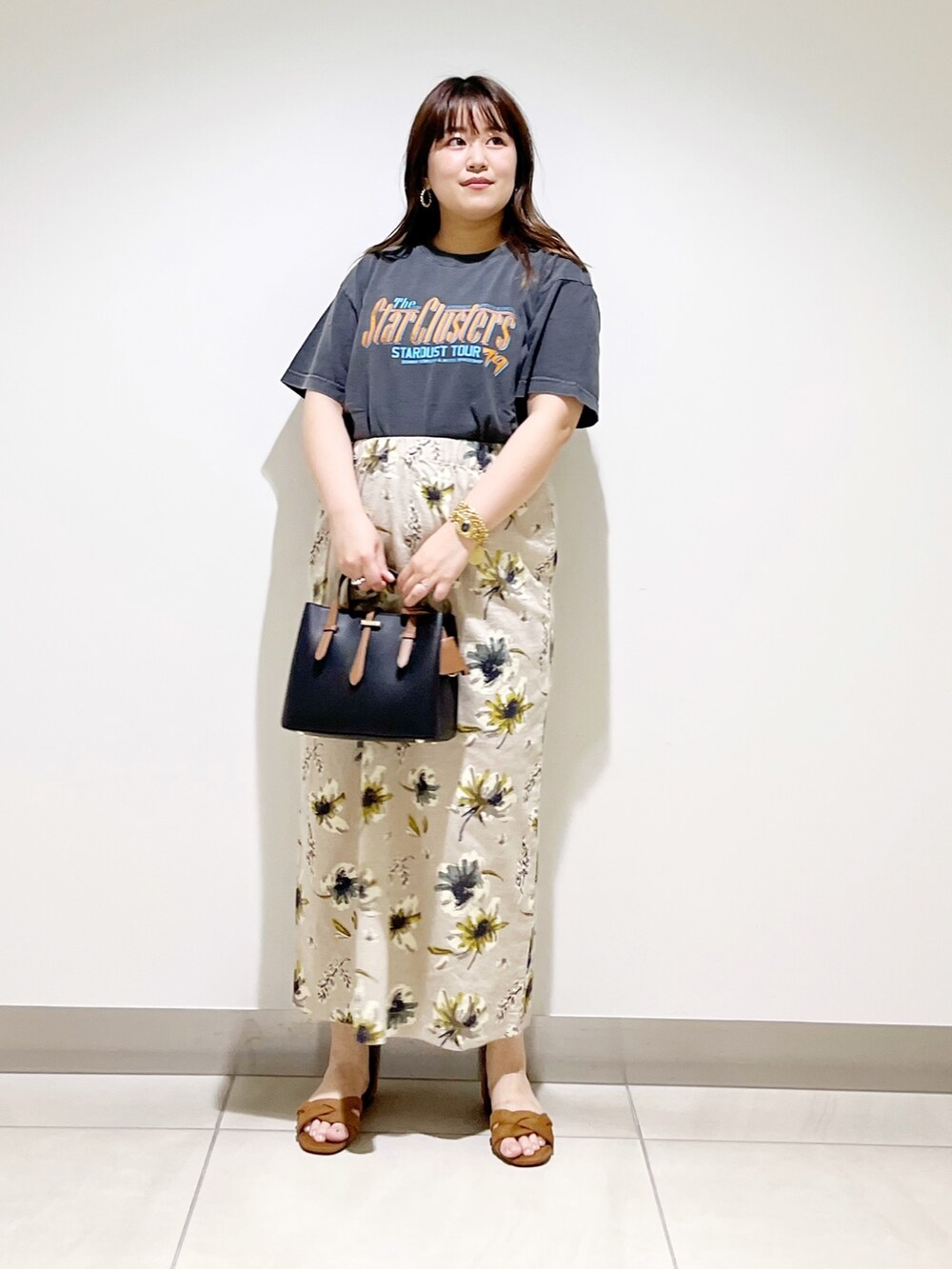 オレンジ系のTシャツ/カットソー、ブラック系のハンドバッグ、イエロー系のスカートを着用したレディースの夏コーディネートの6枚目の写真