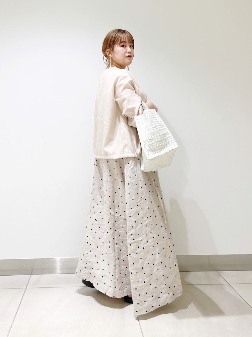 ベージュ系のカーディガン/ボレロ、ベージュ系のワンピース、ホワイト系のトートバッグを着用したレディースの春コーディネートの2枚目の写真