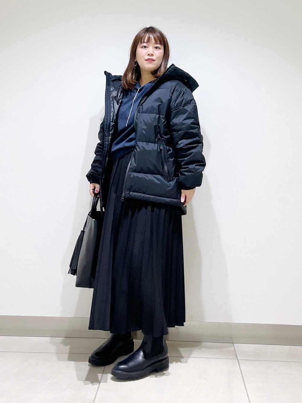 ブラック系のダウンジャケット/コート、ブルー系のTシャツ/カットソー、ブラック系のスカートを着用したレディースの秋コーディネートの8枚目の写真