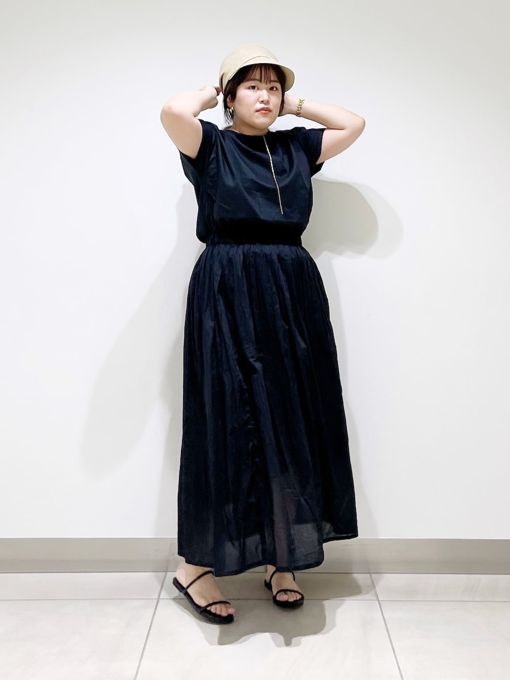 ブラック系のワンピース、ブラック系のサンダル、ベージュ系のキャスケットを着用したレディースの夏コーディネートの3枚目の写真