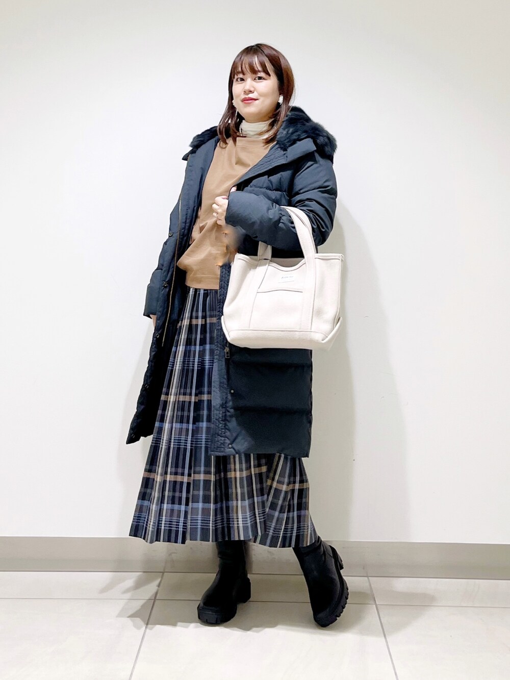 イエロー系のTシャツ/カットソー、ブラック系のダウンジャケット/コート、ブルー系のスカートを着用したレディースの秋コーディネートの5枚目の写真