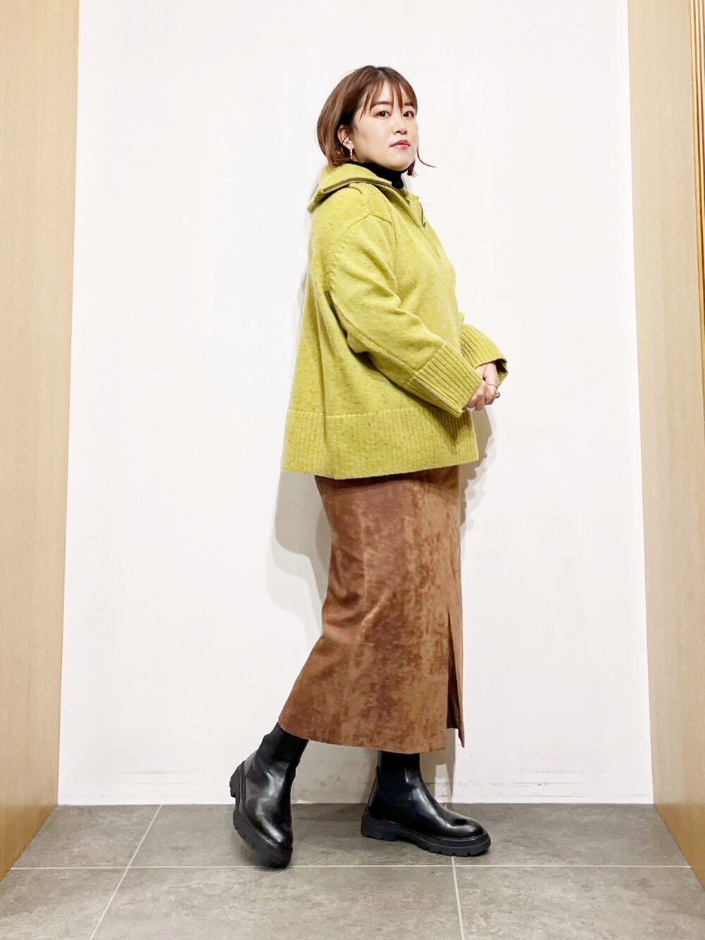 グリーン系のニット/セーター、ブラック系のニット/セーター、ブラウン系のスカートを着用したレディースの冬コーディネートの3枚目の写真