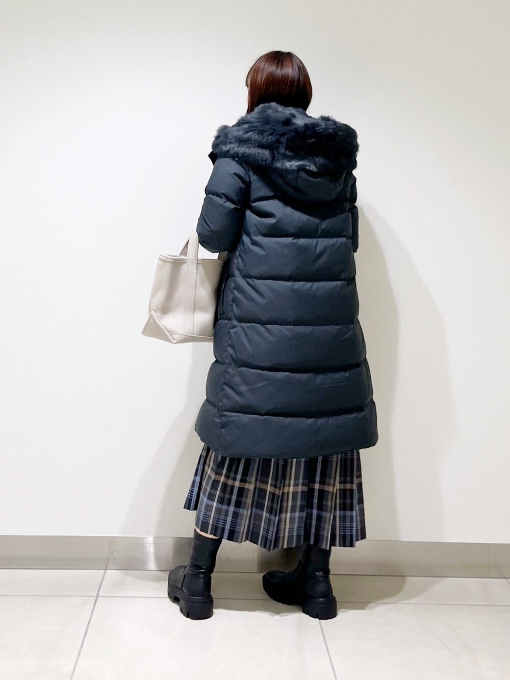 イエロー系のTシャツ/カットソー、ブラック系のダウンジャケット/コート、ブルー系のスカートを着用したレディースの秋コーディネートの3枚目の写真