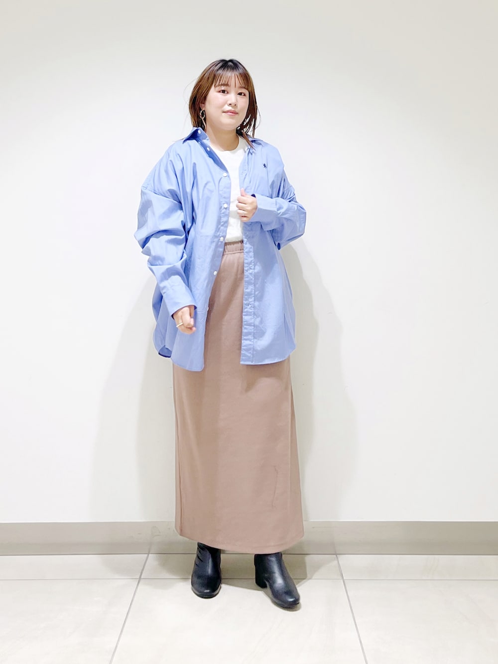 ブルー系のシャツ/ブラウス、ベージュ系のスカート、ブラック系のブーツを着用したレディースの秋コーディネートの3枚目の写真