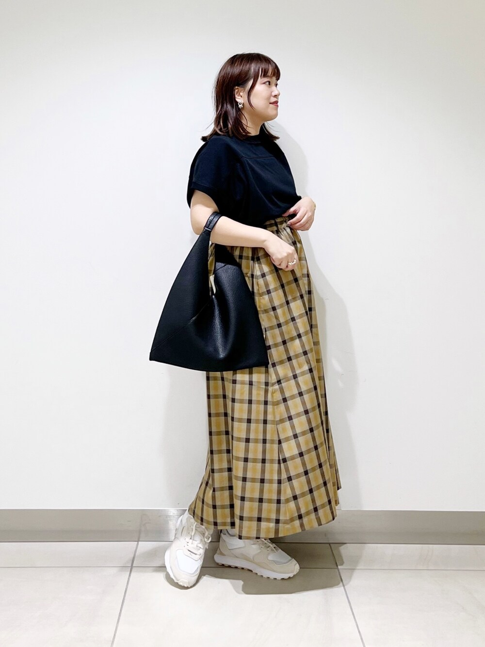 ホワイト系のスニーカー、ブラック系のTシャツ/カットソー、ブラック系のトートバッグを着用したレディースの秋コーディネートの3枚目の写真