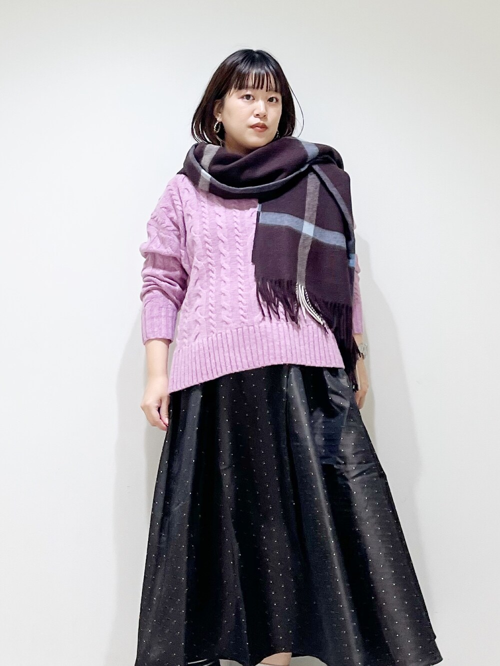 パープル系のニット/セーター、ブルー系のスカート、ブラック系のスニーカーを着用したレディースの秋コーディネートの3枚目の写真