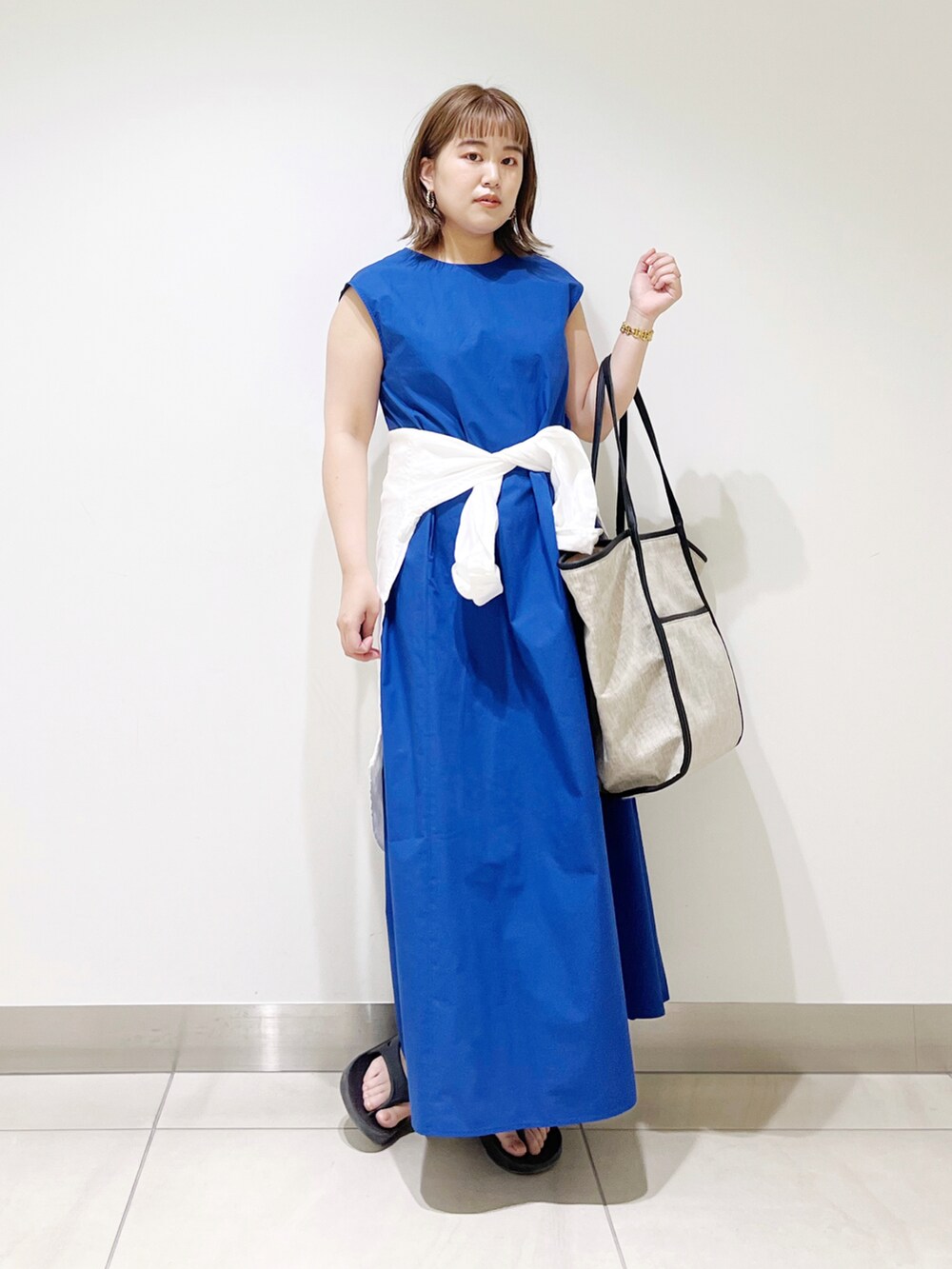 ブルー系のワンピース、ブラック系のトートバッグ、ブラック系のサンダルを着用したレディースの春コーディネートの5枚目の写真