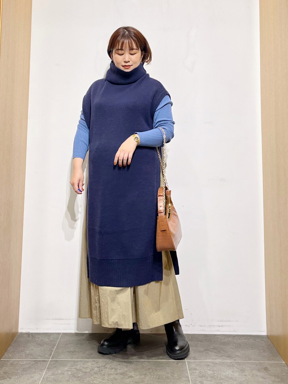 ブルー系のワンピース、ブラック系のブーツ、ベージュ系のスカートを着用したレディースの秋コーディネートの3枚目の写真