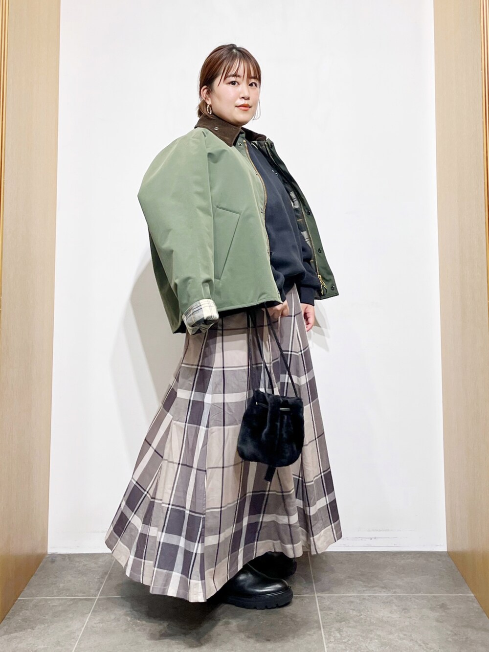 グリーン系のその他アウター、ブラック系のスウェット、ブラック系のハンドバッグを着用したレディースの冬コーディネートの2枚目の写真