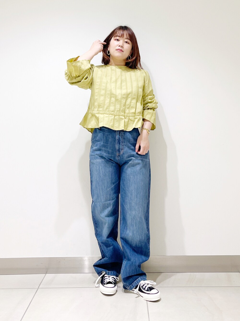 グリーン系のシャツ/ブラウス、ブルー系のデニムパンツ、ブラック系のスニーカーを着用したレディースの春コーディネートの3枚目の写真